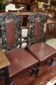 A pair of 19th century Carolean style heavily carved high back chairs with leather covers.