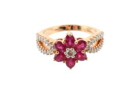 A ruby and diamond cluster ring, the central brilliant cut diamond claw set within a surround of
