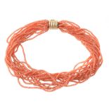 A coral torsade necklace, the multiple strands of uniform coral beads to a reeded barrel clasp,