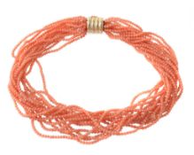 A coral torsade necklace, the multiple strands of uniform coral beads to a reeded barrel clasp,