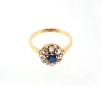 A sapphire and diamond cluster ring, the central circular shaped sapphire claw set within a