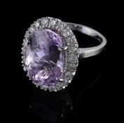 An 18 carat gold kunzite and diamond cluster ring, the central oval shaped kunzite claw set within
