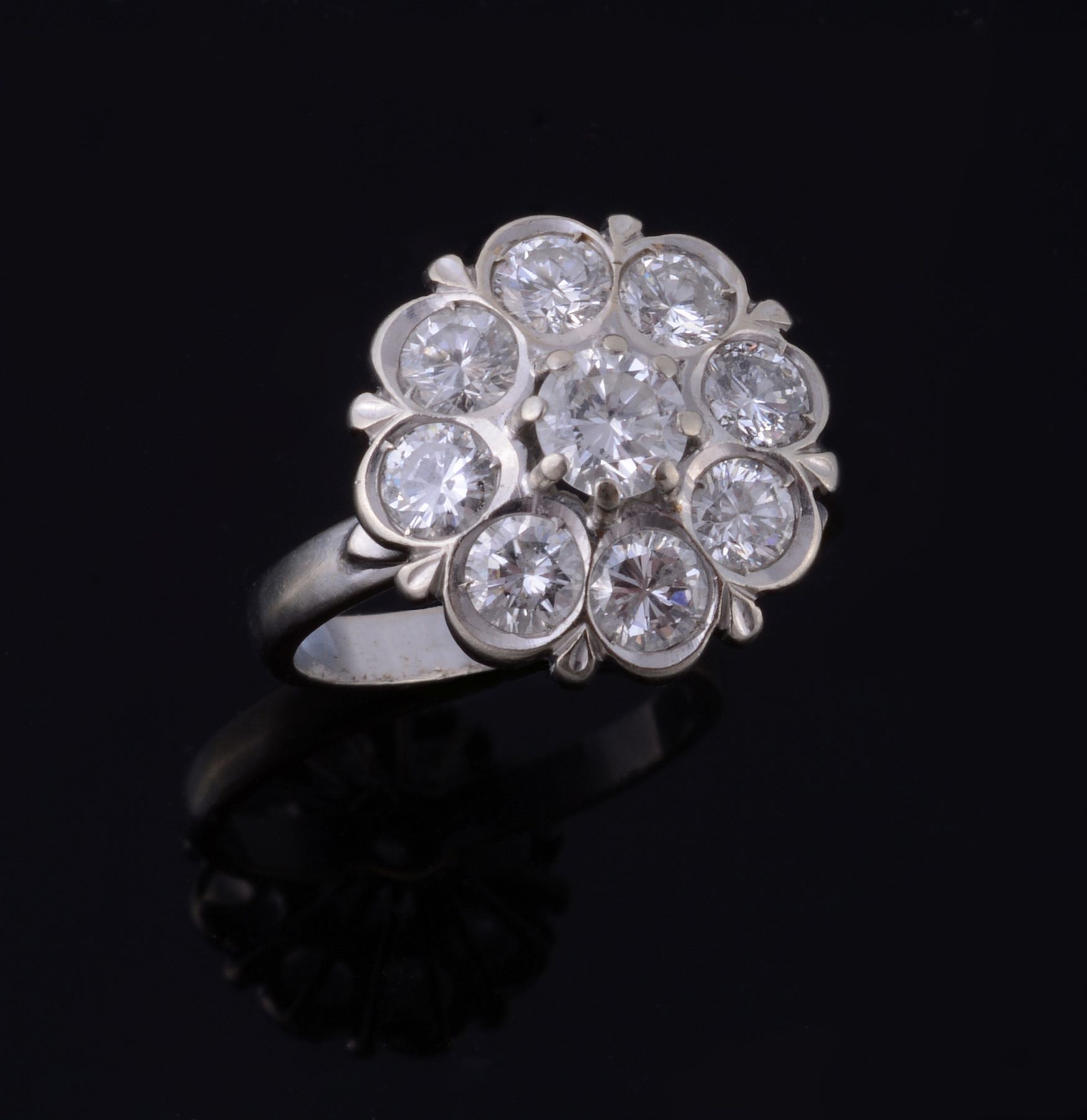 A diamond cluster ring, the central brilliant cut diamond claw set within a surround of brilliant