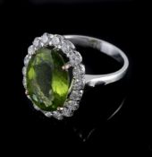 A peridot and diamond cluster ring, the central oval shaped peridot claw set within a surround of