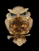 A gem set owl brooch by Cartier, circa 1960, with a mixed cut citrine set body, and emerald and