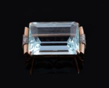 An aquamarine and diamond brooch, circa 1950, the step cut aquamarine with canted corners,