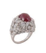 A French ruby and diamond cluster ring, the central oval cabochon ruby claw set within a surround