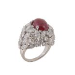 A French ruby and diamond cluster ring, the central oval cabochon ruby claw set within a surround