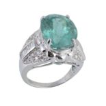 A paraiba tourmaline and diamond ring, the central oval shaped paraiba tourmaline in a raised four