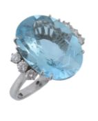 An aquamarine and diamond ring, the central oval shaped aquamarine claw set between brilliant cut