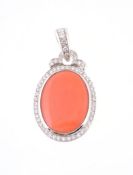 A coral and diamond pendant, the oval cabochon panel within a brilliant cut diamond surround and