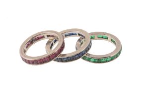 Three gem set eternity rings, each set with either baguette cut rubies, sapphires or emeralds,