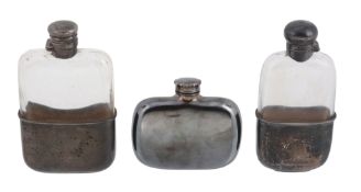 Two Victorian silver mounted clear glass spirit flasks and one electroplated, comprising: the first