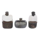 Two Victorian silver mounted clear glass spirit flasks and one electroplated, comprising: the first