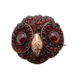 A garnet set owl brooch, the circular brooch designed as an owl head, set throughout with circular