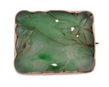 A jadeite brooch, the rectangular panel carved with a lotus flower and leaf, within a collet