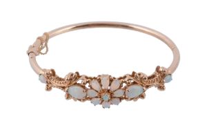 An opal hinged bangle, the central flower head set with a cluster of opals, between two pear shaped