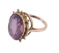 An amethyst ring, the oval shaped amethyst within a collet setting, to a beaded border, finger size