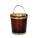 A Mahogany Peat Bucket England circa 1800, with broad brass bands and with hinged brass handle on