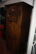 A 20th century oak hall coat cupboard, panelled door with a mirror to the interior. 76cm x 177cm.