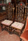 A pair of carved wood high back Jacobean manner side chairs with needle point cushions.