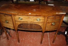 A Georgian bow fronted mahogany sideboard with a tambour front opening flanked by drawers, raised on