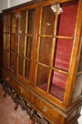 An 18th century style walnut china display cabinet with three sections raised on a richly carved