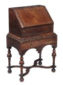 A George II walnut bureau, circa 1740, the book-matched fall opening to an arrangement of drawers,