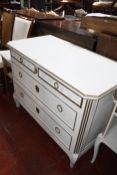 A white painted chest of drawers together with a marble top bedside table.