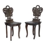 A pair of 'Black Forest' carved and stained wood children's chairs, early 20th century, with foliate
