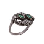 An emerald and diamond ring, the two circular shaped emeralds within a surround of brilliant cut