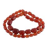 A red amber bead necklace, composed of graduated oval shaped polished red amber beads, 66cm long