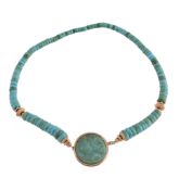 A turquoise necklace, composed of polished turquoise disc beads, the central circular panel carved