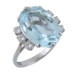 An aquamarine and diamond ring, the central oval shaped aquamarine in a six claw setting, the