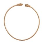 A gold torc necklace, the hollow band set with lion's head to each terminal, the eyes and head set