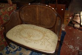 An early 20th century Louis XVI style carved walnut 'bergere' canape with loose needlepoint