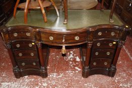 A Victorian design mahogany serpentine desk with a central drawer flanked by eight short drawers and
