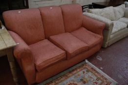 A three seat sofa in coral pink upholstery.180cm wide  Best Bid
