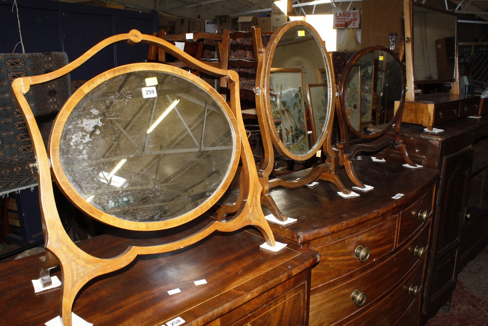 A late Victorian mahogany and inlaid oval swing mirror, together with two further swing mirrors £