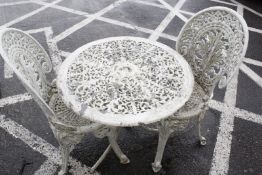 A white wrought iron circular table, two chairs and another wrought iron table