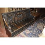 A 19th Century carved oak hall seat, the central panel depicting a tavern scene, with a hinged lid