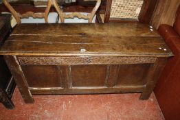 A 17th Century oak coffer, with a hinged lid, carved frieze and triple panel front on stile feet