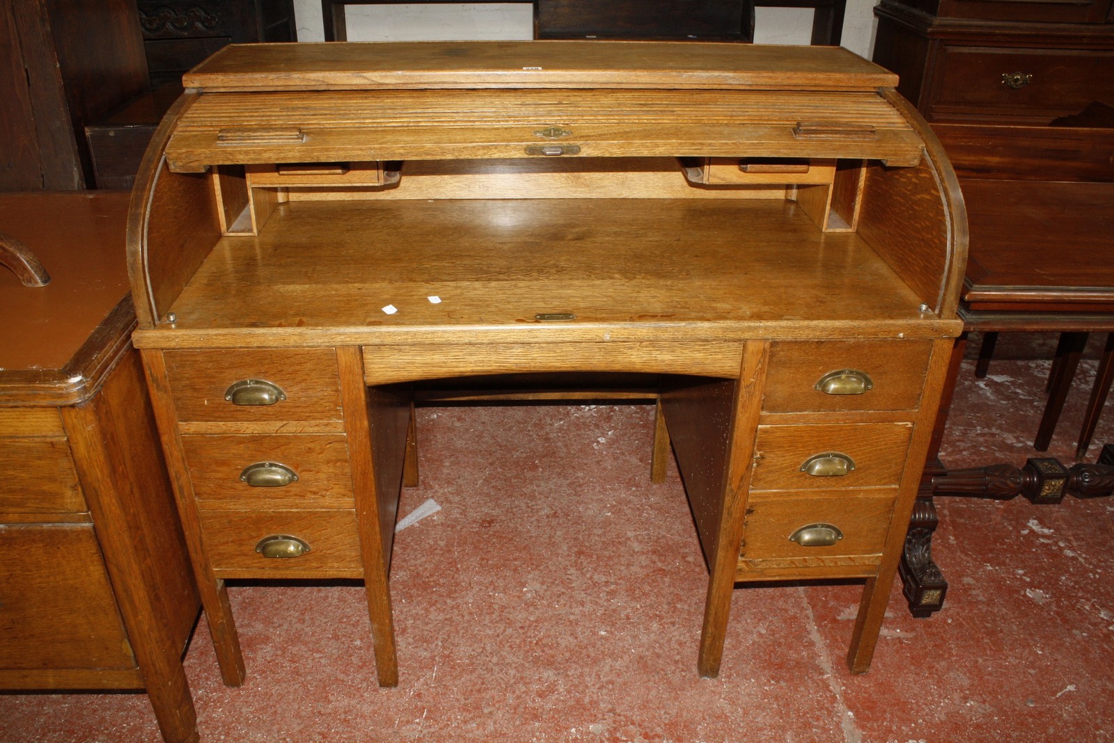 An early 20th Century oak roll top desk, with tambour front and six short drawers on square