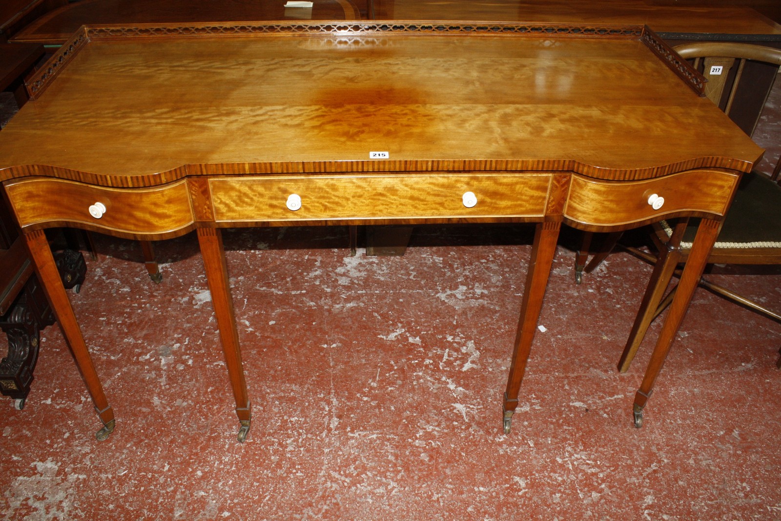 A Sheraton style satinwood and crossbanded writing desk, with a shaped top and three quarter