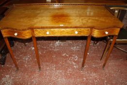 A Sheraton style satinwood and crossbanded writing desk, with a shaped top and three quarter
