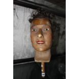 A wax mannequin head of a man with real hair wig, glass eyes, wooden handle 32.5cm (not including