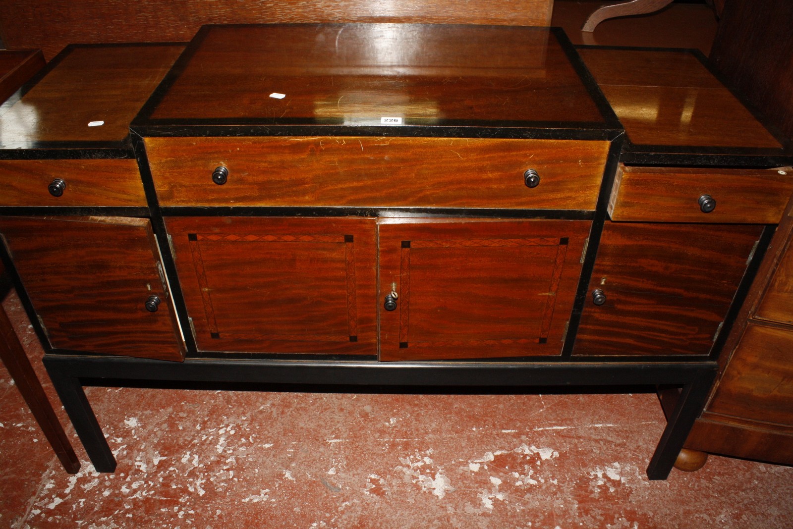 A Heals ebonised and mahogany sideboard, with a stepped top, three short drawers and cupboards below