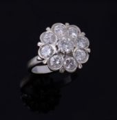 A diamond cluster ring, the central brilliant cut diamond claw set within a...  A diamond cluster