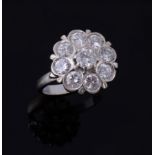 A diamond cluster ring, the central brilliant cut diamond claw set within a...  A diamond cluster