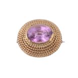 A pink topaz brooch, the oval shaped pink topaz collet set within a...  A pink topaz brooch,   the